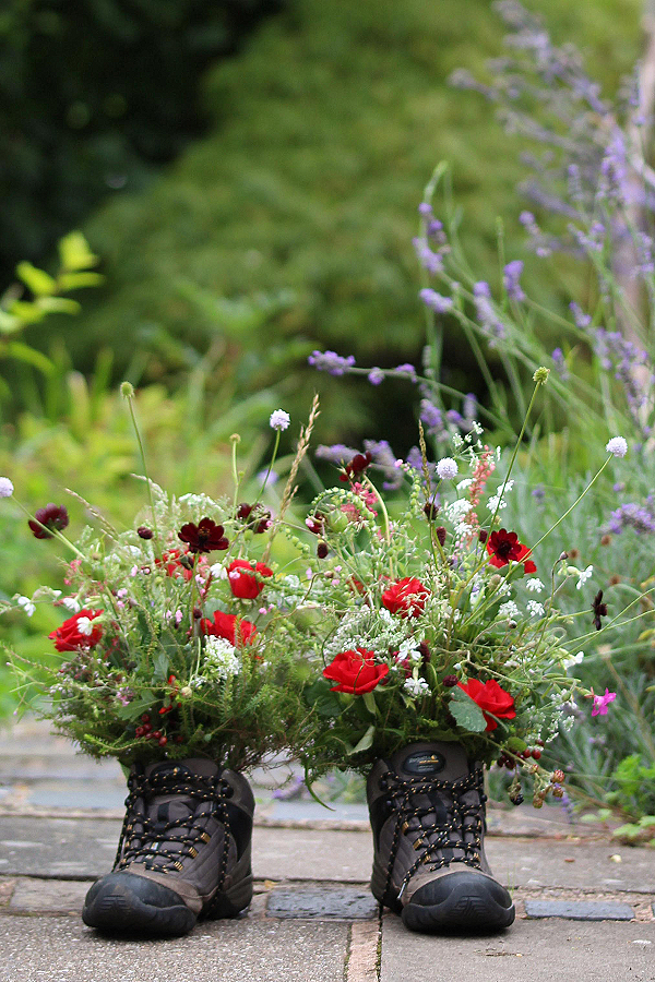 Walking boots filled with wild flowers for the a man who loved walking and the countryside. Funeral flowers by Tuckshop Flowers